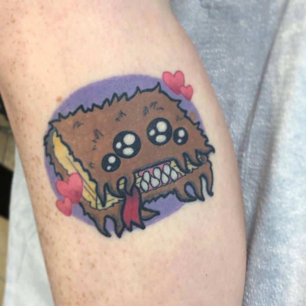 Adorable cartoon-style Monster Book of Monsters tattoo from Harry Potter, featuring a fuzzy cover, sharp teeth, and small heart accents