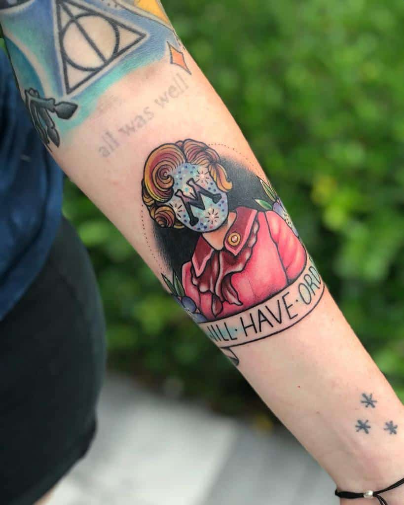 Stylized Dolores Umbridge tattoo from Harry Potter, featuring her pink outfit, a banner reading 'Will Have Order,' and a scribbled-out face with fireworks and letter 'M'