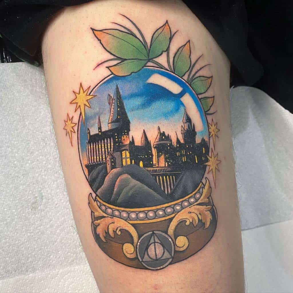 Vibrant Hogwarts castle tattoo inside a magical crystal ball, featuring stars, leaves, and the Deathly Hallows symbol at the base