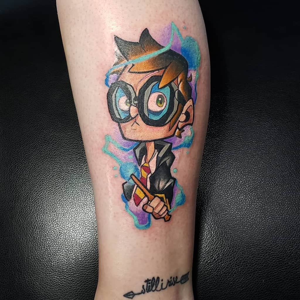 Cartoon-style Harry Potter tattoo featuring oversized glasses, a Gryffindor tie, and a glowing magical aura in vibrant blue and purple hues