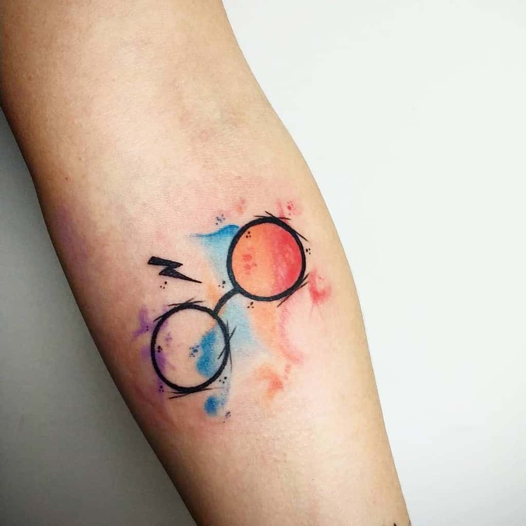 Minimalist Harry Potter tattoo featuring his iconic glasses and lightning scar, with a watercolor background in blue, red, and orange hues
