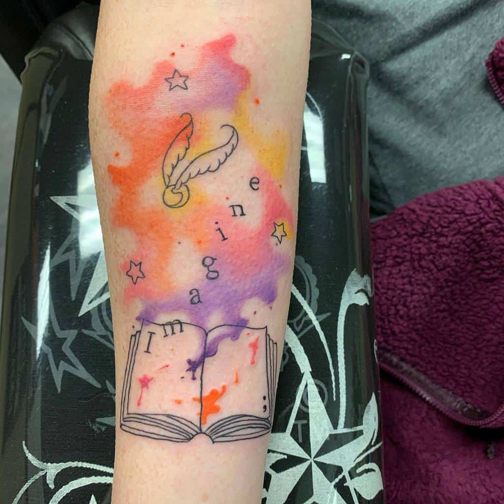 Colorful watercolor tattoo of an open book with the word 'Imagine,' floating stars, and a Golden Snitch, symbolizing creativity and magic