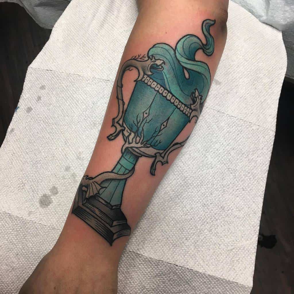 Intricate Triwizard Cup tattoo from Harry Potter, featuring a glowing blue goblet with mystical smoke swirling around its detailed handles