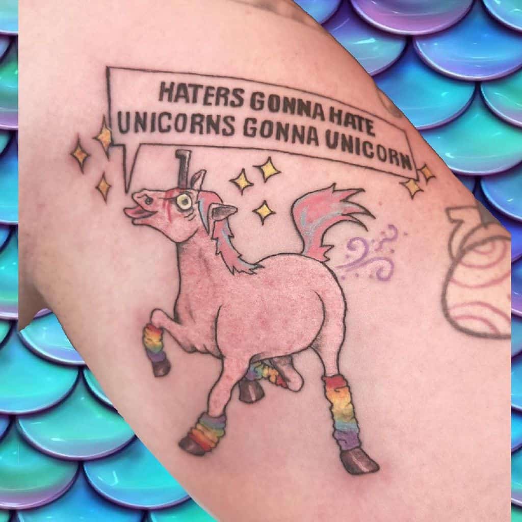Funny tattoo of a derpy unicorn with rainbow leg warmers, sparkles, and a speech bubble saying 'Haters gonna hate, unicorns gonna unicorn.'