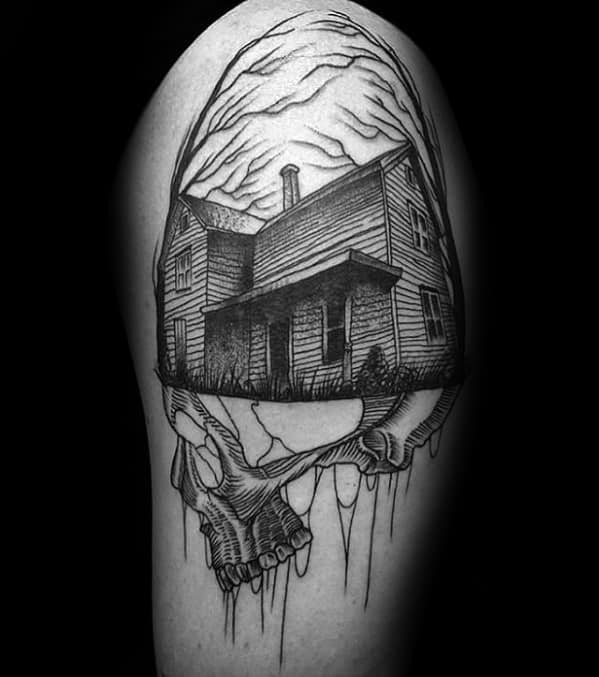 Upper arm tattoo of a creepy wooden house blending into a skull, with dripping ink lines and eerie clouds swirling above.