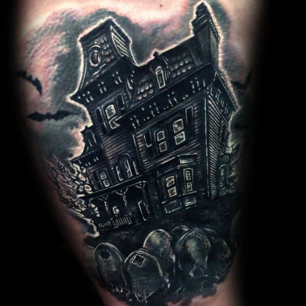 Haunted house tattoo with glowing windows, crooked structure, bats flying, and a graveyard in the foreground under a gloomy sky.