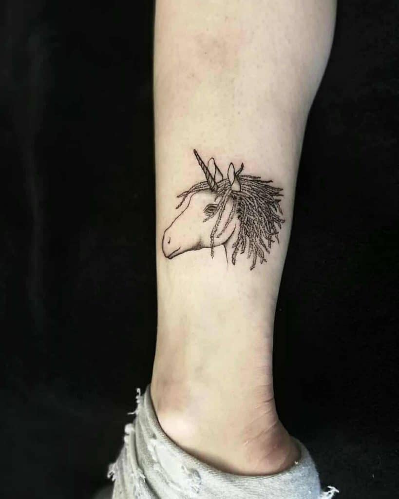 Minimalist unicorn tattoo on the lower leg, featuring fine-line details and a textured mane resembling dreadlocks for a unique touch.