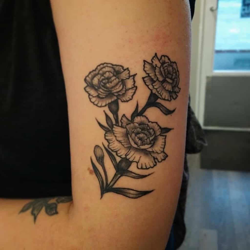 Black and gray tattoo of three carnations, showing detailed petals and leaves