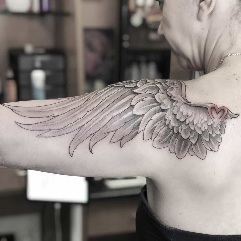 Elegant single angel wing tattoo, featuring detailed feathers and a heart shape formed at the tip of the wings