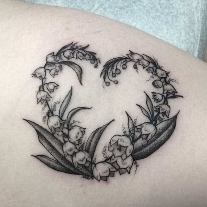 A heart-shaped tattoo composed of lily of the valley flowers and leaves