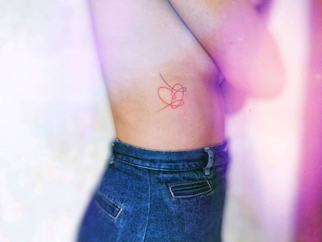 Elegant tattoo featuring a delicate abstract heart in red and black ink