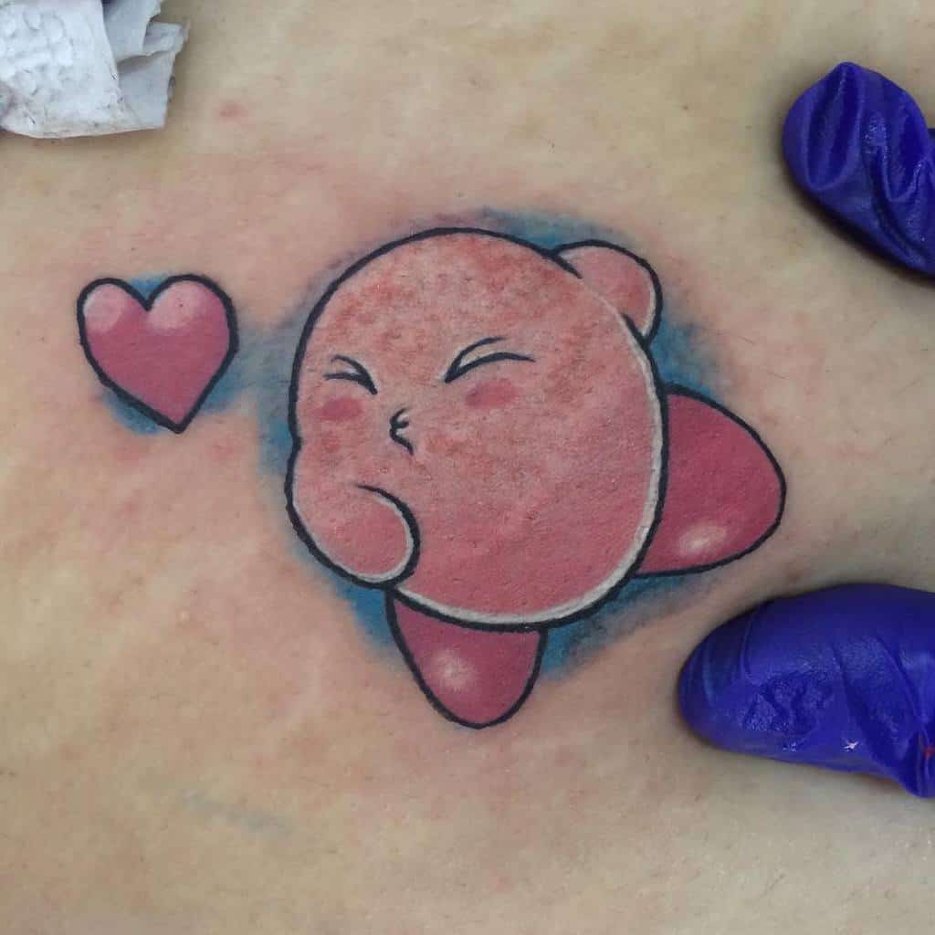 Kirby tattoo blowing a kiss towards a floating heart, soft shading with a blue aura adds depth to this cute and playful design