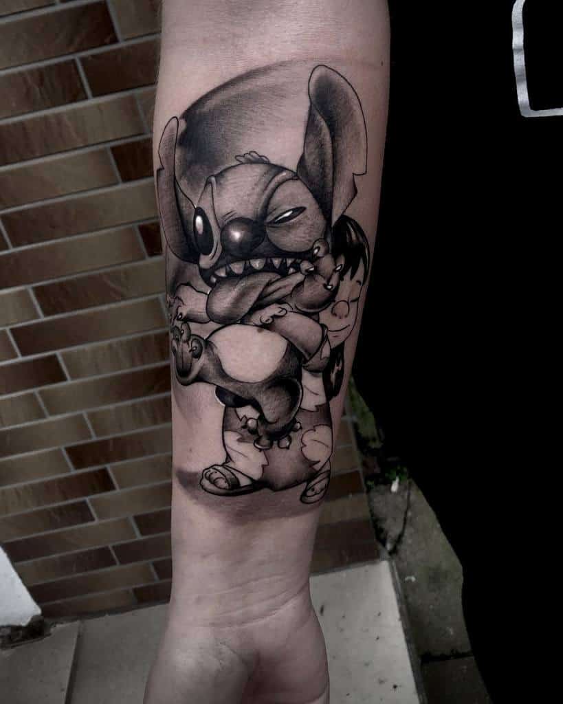 Black and gray tattoo of Stitch from Lilo & Stitch with a mischievous grin, holding a teddy bear while sitting on an arm.