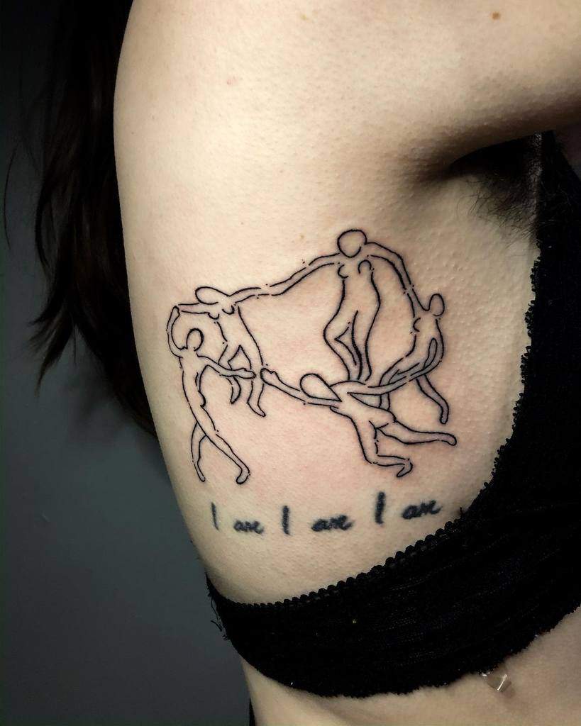 Minimalist black ink tattoo of abstract human figures intertwined in a circular dance, inspired by Matisse's 'The Dance,' with the phrase 'I am I am I am' below.