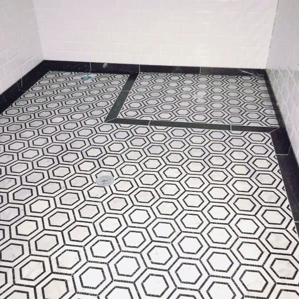 Bathroom with white hexagonal floor tiles outlined in black, creating a bold geometric pattern.