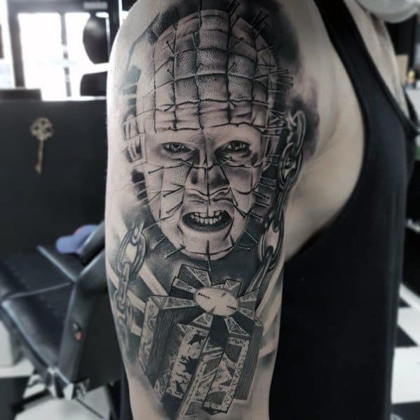 Black and grey *Hellraiser* tattoo of Pinhead with intricate shading, detailed chains, and the Lament Configuration puzzle box for a sinister look.