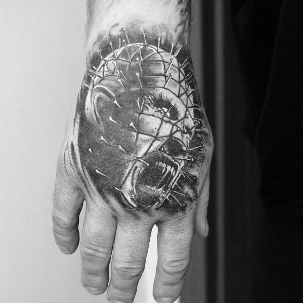 Black and grey *Hellraiser* hand tattoo of Pinhead, featuring a screaming expression, intricate pin details, and intense shading for a bold look.