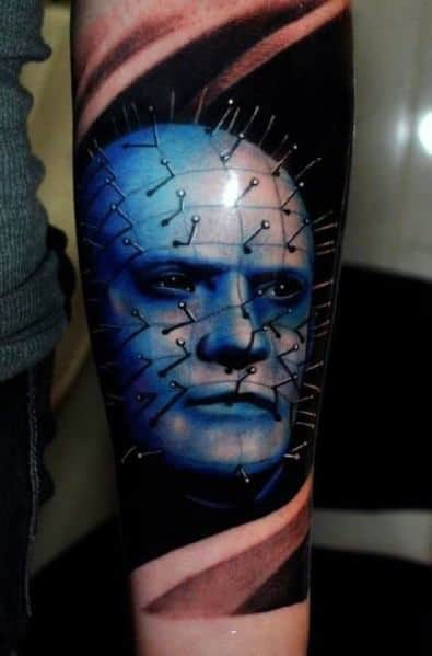 Realistic *Hellraiser* tattoo of Pinhead with a striking blue-toned face, detailed pin grid, and dynamic shading for a bold, eerie effect.