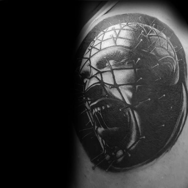 Black and grey *Hellraiser* tattoo of Pinhead screaming, featuring intense shading, intricate pin details, and a dark, haunting atmosphere.