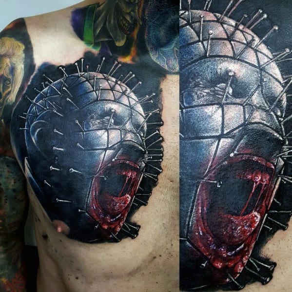 Hyper-realistic *Hellraiser* chest tattoo of Pinhead screaming, featuring deep shading, blood-red details, and metallic pin reflections for a brutal look.