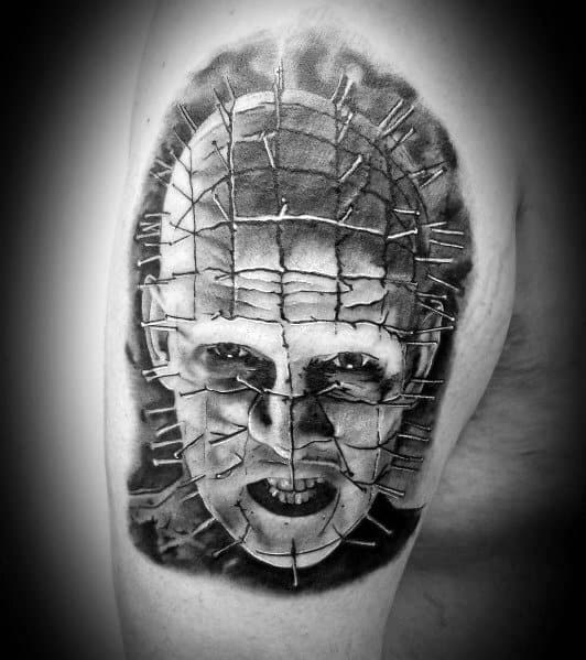 Black and grey *Hellraiser* tattoo of Pinhead with intense shading, detailed pin grid, and a menacing expression for a striking horror design.