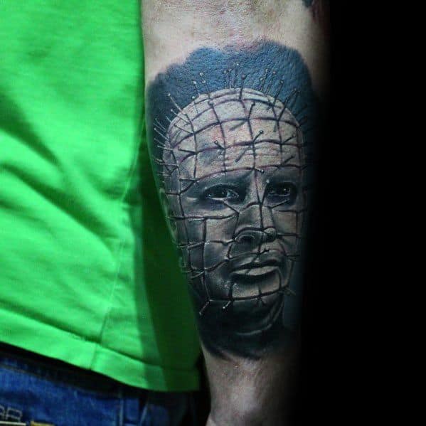Realistic *Hellraiser* tattoo of Pinhead with intricate pin grid, deep shading, and an intense expression, creating a dark and eerie atmosphere.
