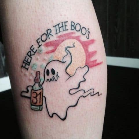 A colorful tattoo of a ghost holding a bottle labeled '31,' with the phrase 'Here for the Boo's' above, blending Halloween and drinking humor.