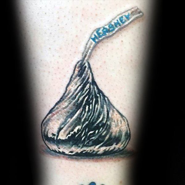 Realistic Hershey's Kiss tattoo with detailed shading and highlights, creating a lifelike metallic foil effect and signature paper tag.
