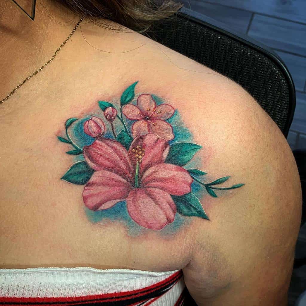 A vibrant hibiscus flower tattoo blossoms with buds and lush leaves