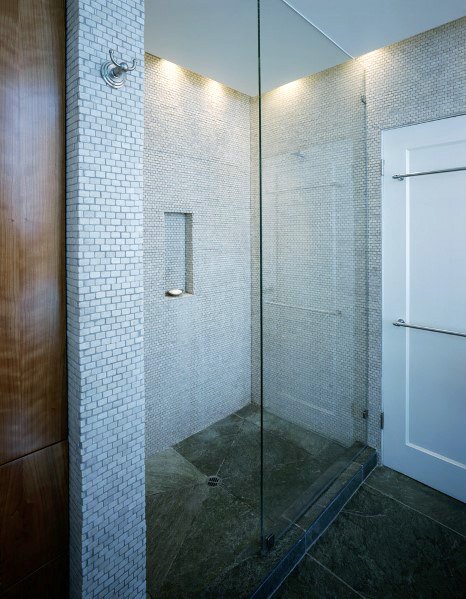 Elegant shower with hidden LED lighting along the ceiling, showcasing sleek mosaic tiles and a minimalist glass enclosure