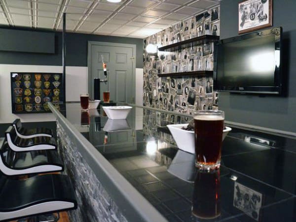 Chic home bar with black countertop, two bowls, beers, wall art, and TV for a perfect lounge vibe