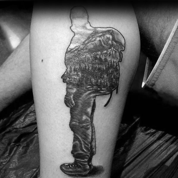 A black and gray tattoo of a hiker with a mountain and forest landscape integrated into their silhouette, symbolizing adventure and exploration.