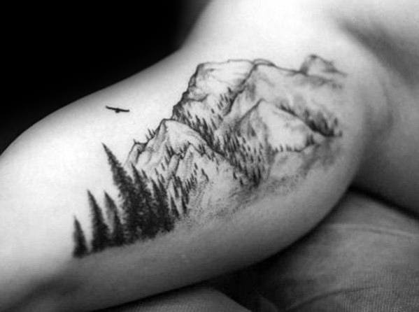 Realistic mountain tattoo with pine trees and a soaring bird, symbolizing freedom, adventure, and a deep connection to nature.