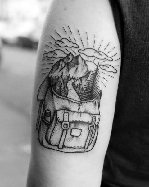 Creative black and white tattoo of a backpack with mountains, trees, and a winding trail emerging, symbolizing adventure and exploration.