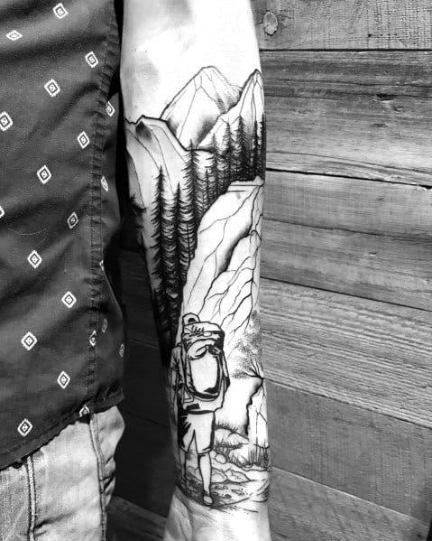 Black and white hiking tattoo of a backpacker on a forest trail with mountains and trees, symbolizing adventure and exploration.