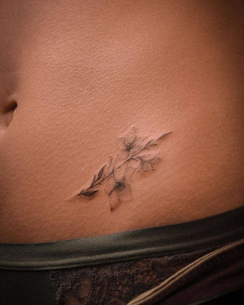 Delicate fine-line floral tattoo, featuring soft shading and intricate details of blooming flowers and leaves