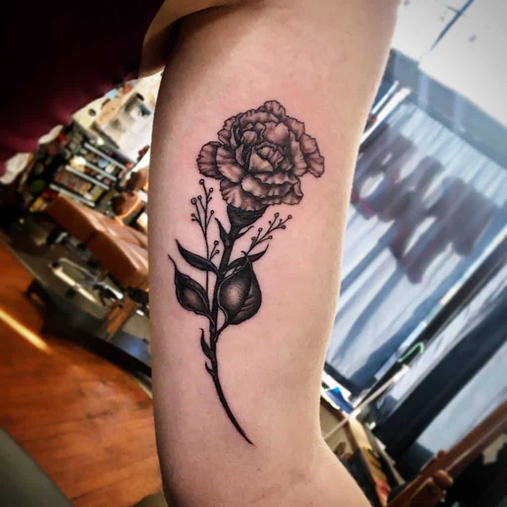 Black and gray carnation tattoo with leaves and small decorative branches 