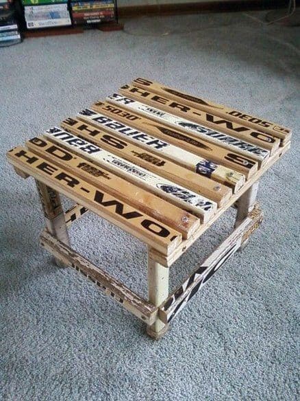 A small wooden table made from repurposed hockey sticks on a light carpeted floor