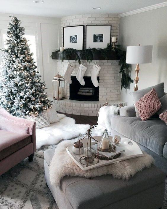 Festive living room with white brick corner fireplace, stockings, garland, and a decorated Christmas tree.