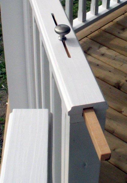 White wooden deck railing with a retractable gate secured by a knob