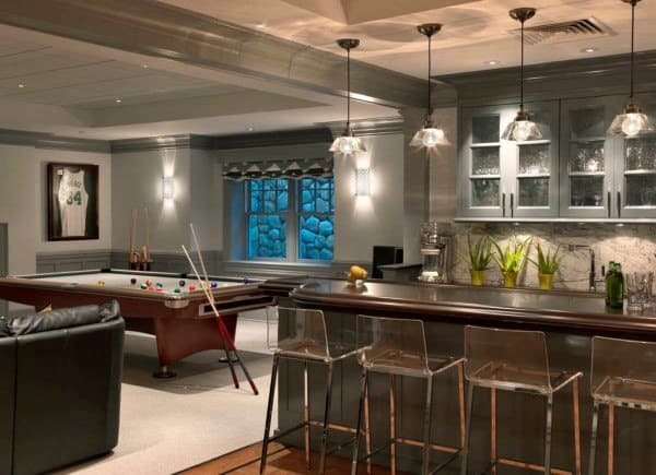 Basement bar with glass cabinets, leather seating, pool table, and industrial pendant lights.