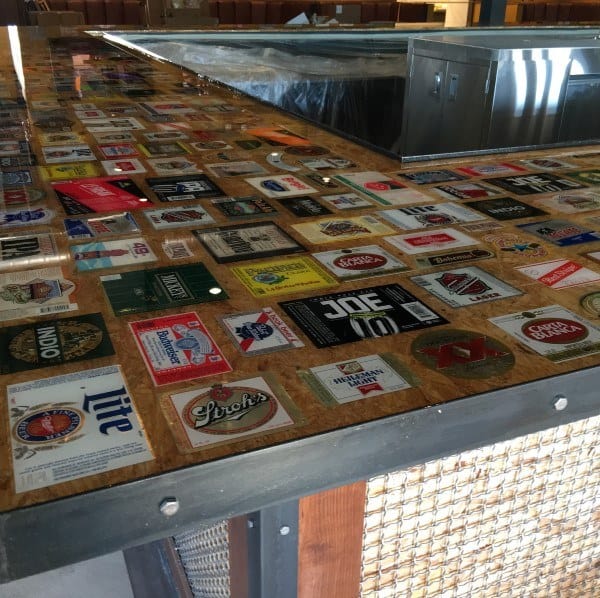 Polished live edge wood slab bar top with sleek black base in a modern industrial setting.