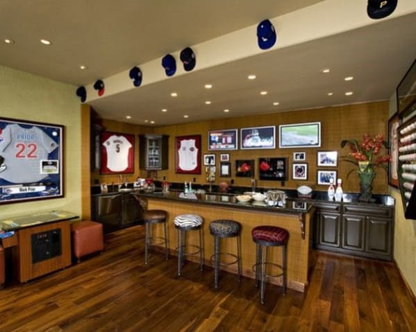 Cozy sports-themed bar with memorabilia, framed jerseys, bar stools, and overhead caps