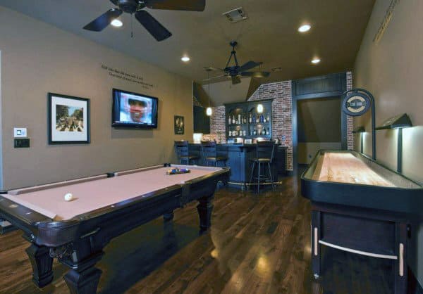 Game room with a pool table, shuffleboard, TV, ceiling fans, and a cozy bar in the corner with brick accents