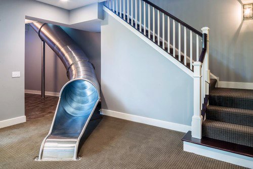 A sleek slide beside a carpeted staircase in a modern interior room