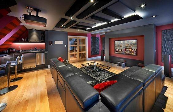 Modern home theater with black leather sectional, projector, and ambient ceiling lighting.