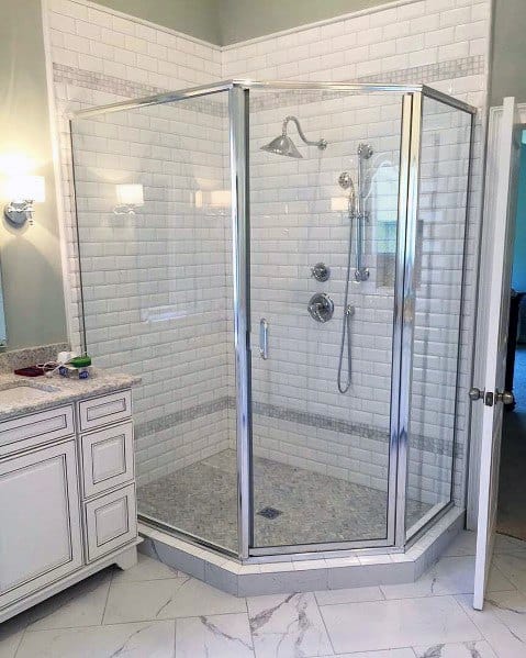 Corner glass shower enclosure with white subway tiles and silver fixtures in a modern bathroom