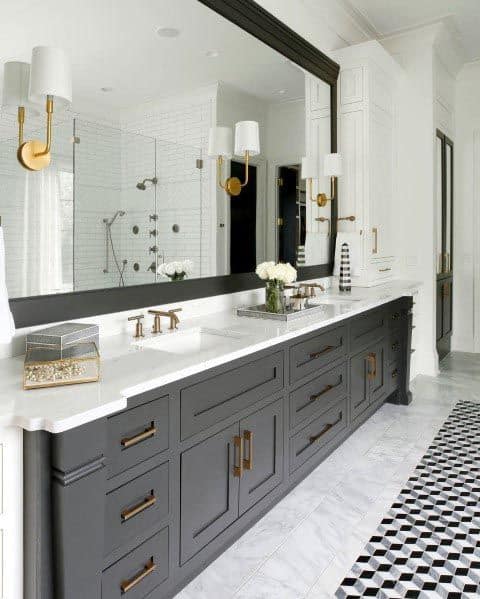 Modern grey bathroom vanity with gold accents, a white marble countertop, and a large black-framed mirror.