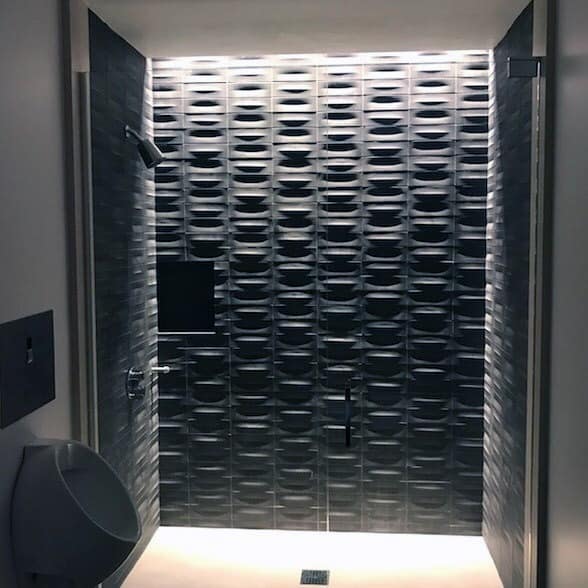 Modern shower with a stunning textured wall and ambient LED lighting, creating a sleek, futuristic look