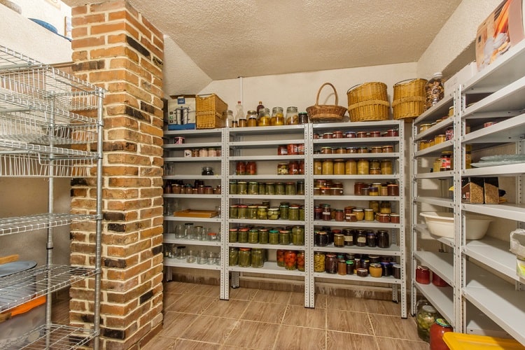Basement pantry with shelves storing home-canned food and jars next to brick column.